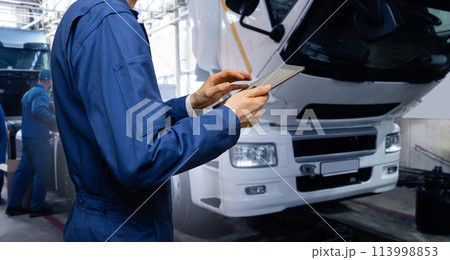Serviceman with digital tablet on the background of the truck in the garage.. 113998853