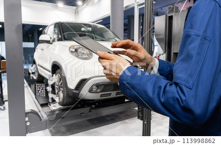 Serviceman with digital tablet on the background of the car in the car service Serviceman with digital tablet on the background of the car in the car service 113998862