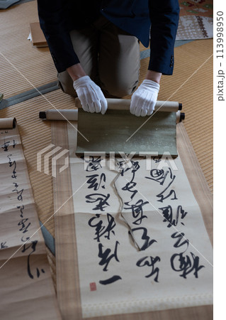 古い掛け軸を鑑定している男性 古い掛け軸を鑑定している男性 113998950