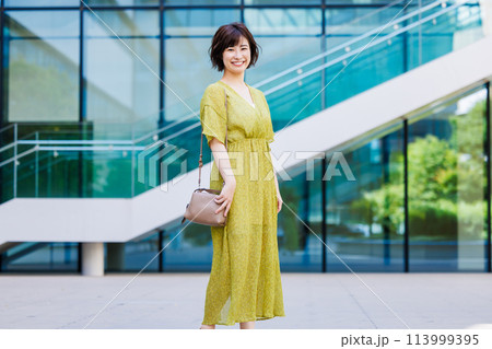 屋外を歩くワンピース姿の若い女性 屋外を歩くワンピース姿の若い女性 113999395