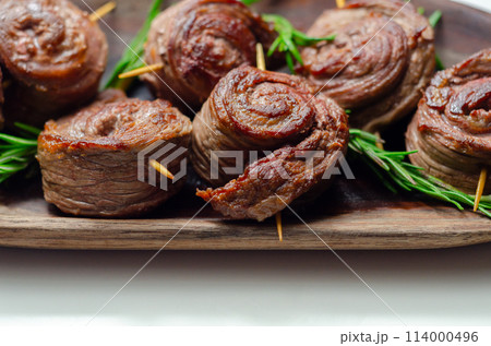 A plate of pieces of meat in the shape of roses with green herbs on top 114000496