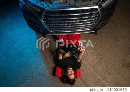 a beautiful girl in a uniform repairs a car at a car service station a beautiful girl in a uniform repairs a car at a car service station 114001656