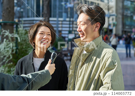 街頭インタビューを受ける男女 114003772