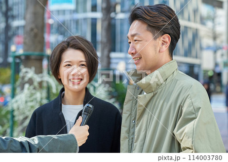街頭インタビューを受ける男女 114003780