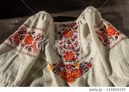 Ukrainian clothes embroidered shirt. Red orange and black threads background. Vyshyvanka is a symbol of Ukraine. Embroidery cross stitching. National Ukrainian stitch. Traditional clothing symbol Ukrainian clothes embroidered shirt. Red orange and black threads background. Vyshyvanka is a symbol of Ukraine. Embroidery cross stitching. National Ukrainian stitch. Traditional clothing symbol 114004295