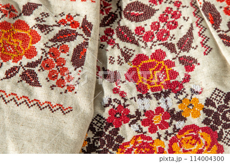 Ukrainian clothes embroidered shirt. Red orange and black threads background. Vyshyvanka is a symbol of Ukraine. Embroidery cross stitching. National Ukrainian stitch. Traditional clothing symbol 114004300