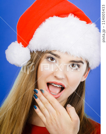 Shocked woman wearing Santa Claus helper costume 114005433