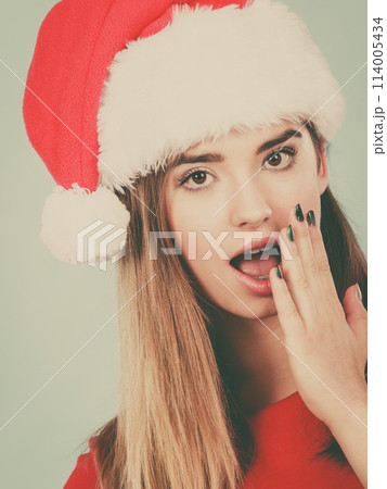 Shocked woman wearing Santa Claus helper costume 114005434