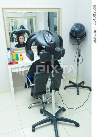 Woman in hairdresser, drying hair under machine 114005659