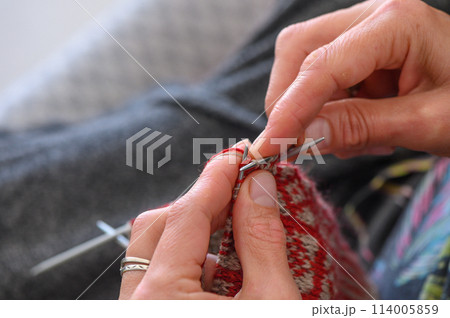 woman sitting on sofa, skillfully knitting warm socks woman sitting on sofa, skillfully knitting warm socks 114005859