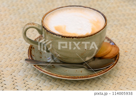 Cup of cappuccino on a table in a cafe. Beautiful foam, white ceramic cup, copy space. Cup of cappuccino on a table in a cafe. Beautiful foam, white ceramic cup, copy space. 114005938