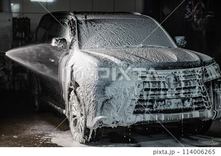 Man applying foam to black car in car wash. Man applying foam to black car in car wash. 114006265