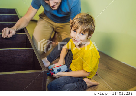 Father and son assembling furniture. Boy helping his dad at home. Happy Family concept Father and son assembling furniture. Boy helping his dad at home. Happy Family concept 114011232