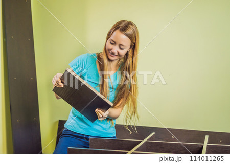 Caucasian woman using screwdriver for assembling furniture 114011265