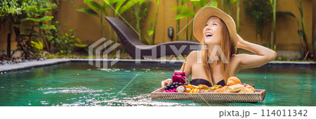 BANNER, LONG FORMAT Breakfast tray in swimming pool, floating breakfast in luxury hotel. Girl relaxing in the pool drinking smoothies and eating fruit plate, smoothie bowl by the hotel pool. Exotic BANNER, LONG FORMAT Breakfast tray in swimming pool, floating breakfast in luxury hotel. Girl relaxing in the pool drinking smoothies and eating fruit plate, smoothie bowl by the hotel pool. Exotic 114011342