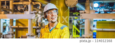Young man in a yellow work uniform, glasses and helmet in industrial environment,oil Platform or liquefied gas plant BANNER, LONG FORMAT 114012168
