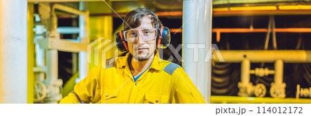 Young man in a yellow work uniform, glasses and helmet in industrial environment,oil Platform or liquefied gas plant BANNER, LONG FORMAT Young man in a yellow work uniform, glasses and helmet in industrial environment,oil Platform or liquefied gas plant BANNER, LONG FORMAT 114012172