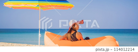 Summer lifestyle portrait of pretty girl sitting on the orange inflatable sofa on the beach of tropical island. Relaxing and enjoying life on air bed BANNER, LONG FORMAT 114012214