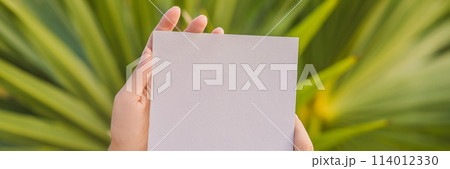 Women's hands in a tropical background holding a signboard paper, mockup BANNER, LONG FORMAT 114012330