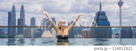 Young woman in outdoor swimming pool with city view in blue sky. Rich people BANNER, LONG FORMAT 114012822
