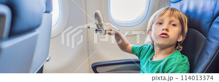 Little boy play with toy plane in the commercial jet airplane flying on vacation BANNER, LONG FORMAT 114013374