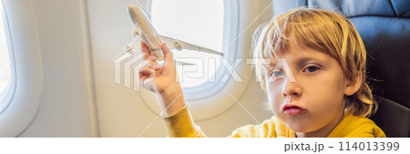 Little boy play with toy plane in the commercial jet airplane flying on vacation BANNER, LONG FORMAT 114013399