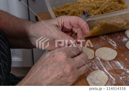 On the wooden counter top are Woman hands are making a damp dumpling 114014338