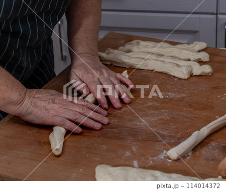 Female hands knead the dough on a wooden table 114014372