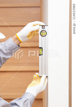 水平器（水準器、レベル）を使って壁の垂直を調べる作業員 114015960