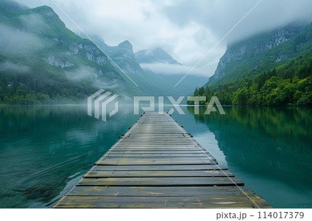 Peaceful lake bordered by a humble wooden pier, with serene mountains rising in the background Peaceful lake bordered by a humble wooden pier, with serene mountains rising in the background 114017379