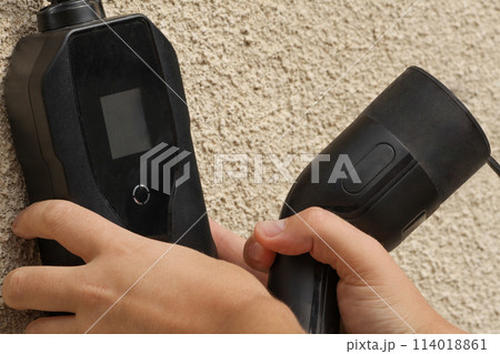 New 2023 new model black portable charger for cars sitting on a gray wall. New 2023 new model black portable charger for cars sitting on a gray wall. 114018861