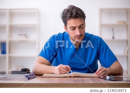 Young male doctor student reading book in the clinic Young male doctor student reading book in the clinic 114019971