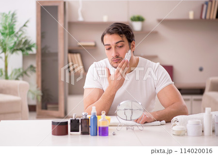 Young man shaving face at home 114020016