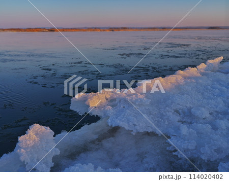 厳冬の北海道十勝川河口　薄氷流れる河面と凍った川岸 114020402