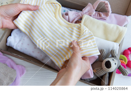 Women's hands collect children's clothes into boxes. Women's hands collect children's clothes into boxes. 114020864