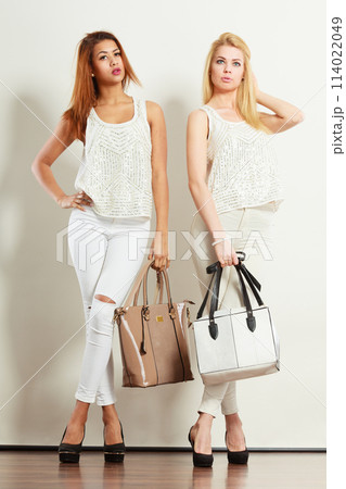 Two women in white clothes with bags handbags. 114022049