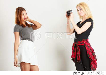 Blonde girl photographing mulatto woman 114022265