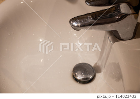 Close up of bathroom sink with running water from faucet Close up of bathroom sink with running water from faucet 114022432