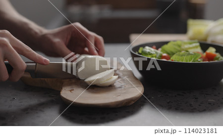 man hands slicing mozzarella on wood board on home kitchen 114023181