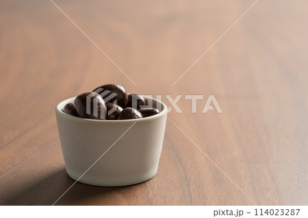 Chocolate covered cashew nuts in a bowl on wood table 114023287