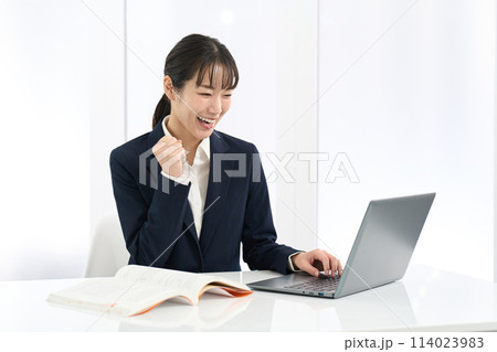 パソコンの前でガッツポーズをする女性 114023983