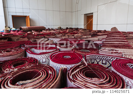 stack of rolled up traditional vintage Uzbek red carpets oriental bazaar for sale in Tashkent in Uzbekistan 114025071