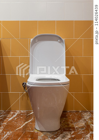 White toilet with yellow tiles, marble flooring, rectangle toilet seat and opened lid White toilet with yellow tiles, marble flooring, rectangle toilet seat and opened lid 114026439