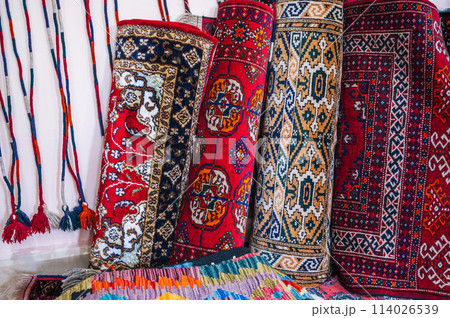 stack of rolled up traditional oriental uzbek handmade carpets at the market in Uzbekistan 114026539