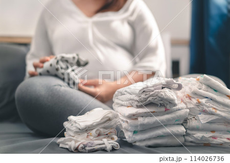 Pregnant asian woman prepare fold baby clothes for planning new born baby, Prepare before Give birth baby concept. 114026736