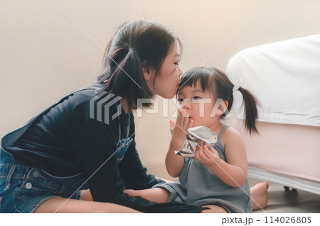 Asian older sister kissing younger sister on the forehead. Sibling relationship 114026805