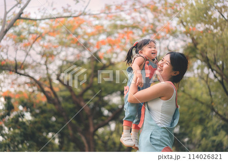 Asian mother walking with daughter in park, Parents hold the baby's in his hand , Happy family in the park evening light, Happy family concept. Asian mother walking with daughter in park, Parents hold the baby's in his hand , Happy family in the park evening light, Happy family concept. 114026821