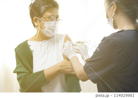 Elderly Asian woman getting coronavirus vaccine by nurse. Medical worker prepare syringe. Elderly Asian woman getting coronavirus vaccine by nurse. Medical worker prepare syringe. 114029981