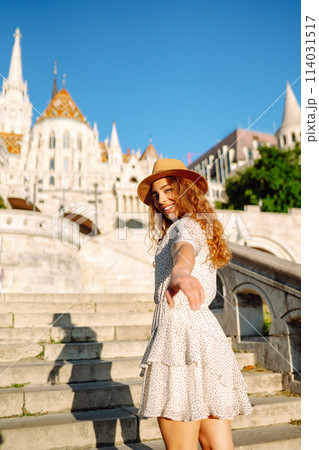 Happy young woman in hat at dawn enjoys view of beautiful buildings. Lifestyle, recreation concept. 114031517