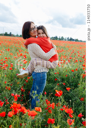 mother holding a daughter in arms in a field full of poppies flowers mother holding a daughter in arms in a field full of poppies flowers 114033750